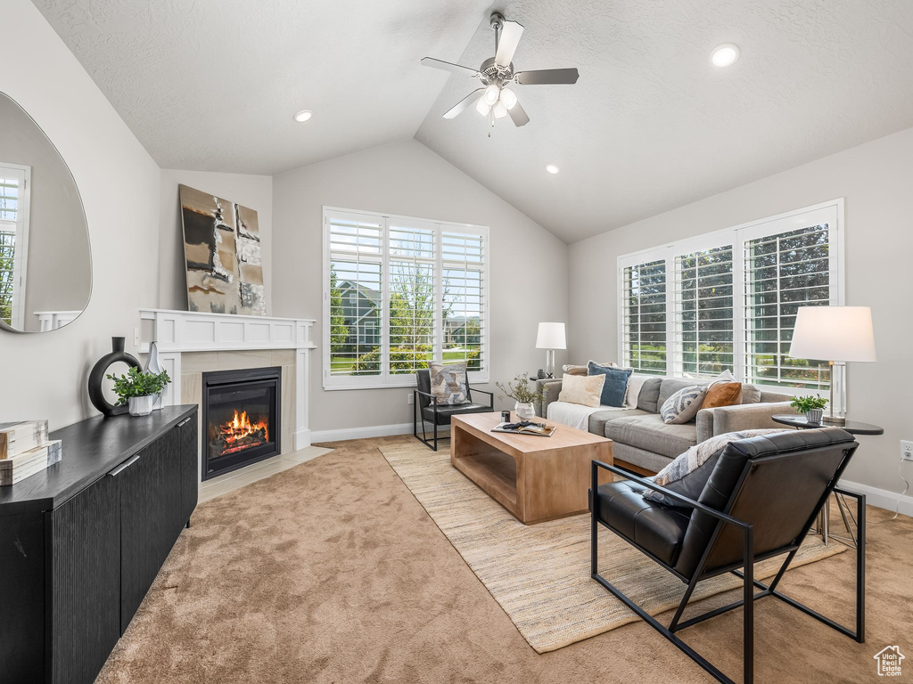 Living area featuring a fireplace with flush hearth, a ceiling fan, plenty of natural light, light carpet, and lofted ceiling