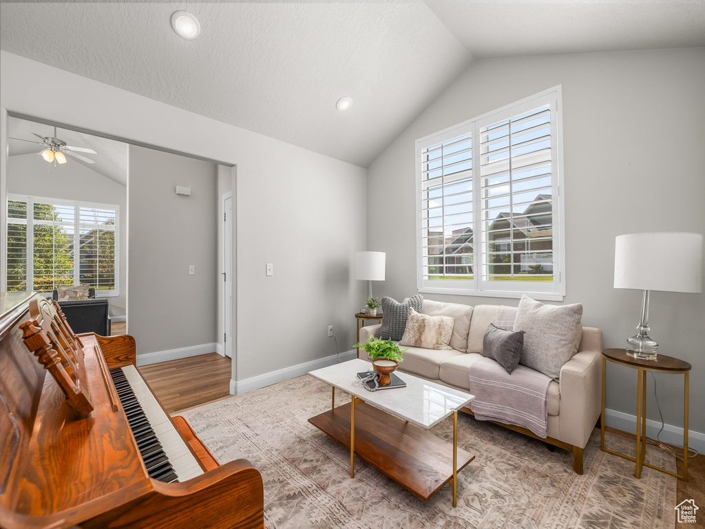 Living room featuring vaulted ceiling, ceiling fan, wood finished floors, and recessed lighting