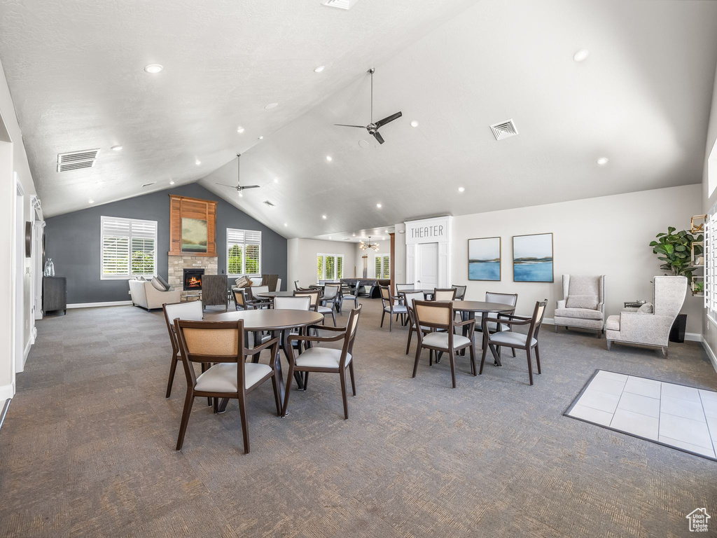 Dining room featuring carpet floors, a fireplace, a ceiling fan, and high vaulted ceiling