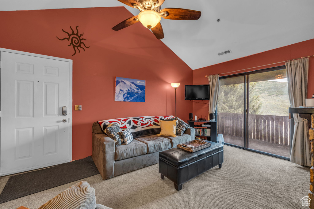 Carpeted living room featuring ceiling fan and high vaulted ceiling