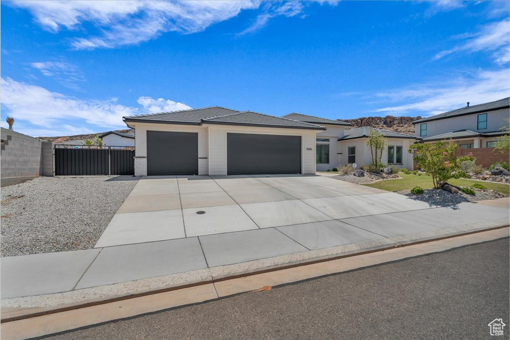 View of front of house featuring an attached garage, driveway, stucco siding, and a tiled roof