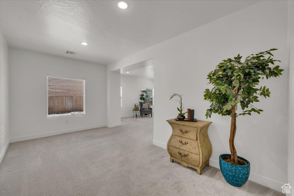 Empty room with light colored carpet and recessed lighting