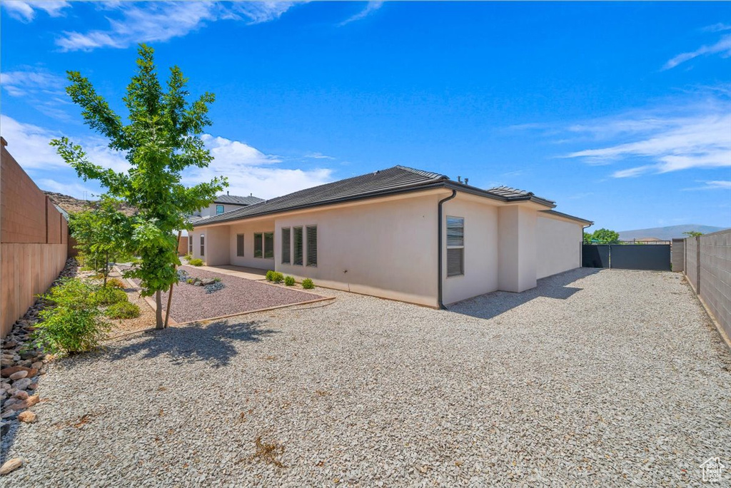 Rear view of property with stucco siding, a fenced backyard, and a patio area