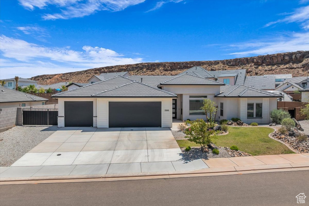 View of front of property with a garage, a mountain view, driveway, and stucco siding