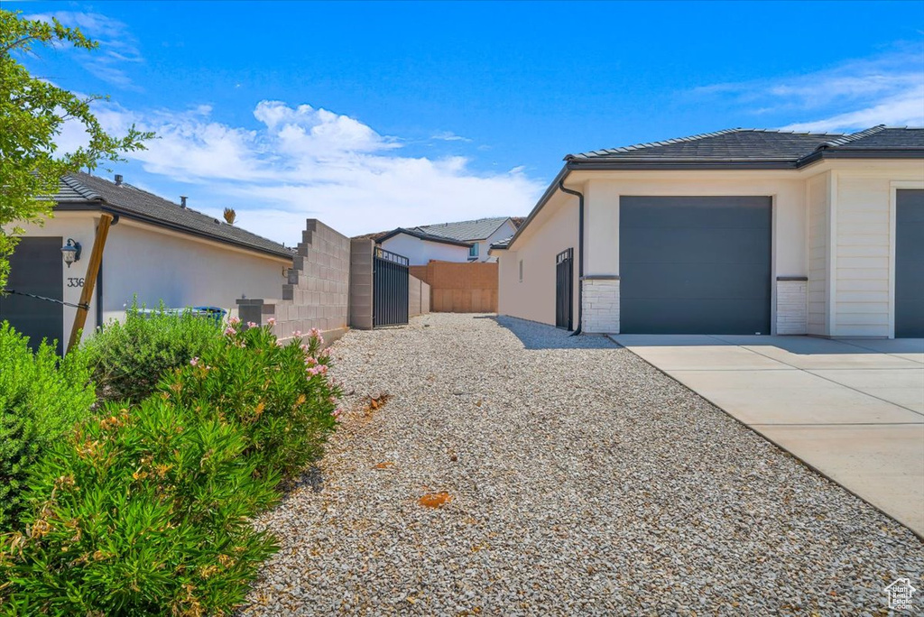 View of property exterior with concrete driveway, a gate, an attached garage, and stucco siding