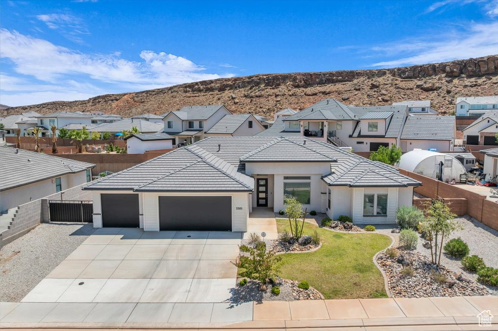 View of front of property featuring driveway, a residential view, a garage, a mountain view, and a tiled roof