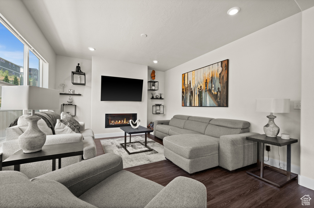Living area with recessed lighting, dark wood-style floors, and a glass covered fireplace