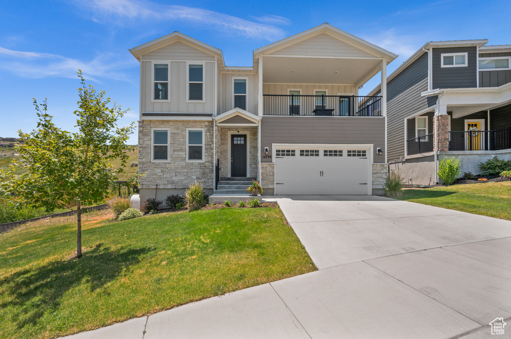View of front of house featuring a balcony, board and batten siding, stone siding, and a garage
