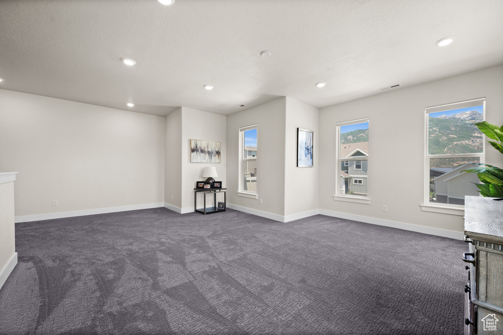 Unfurnished living room featuring dark colored carpet and recessed lighting