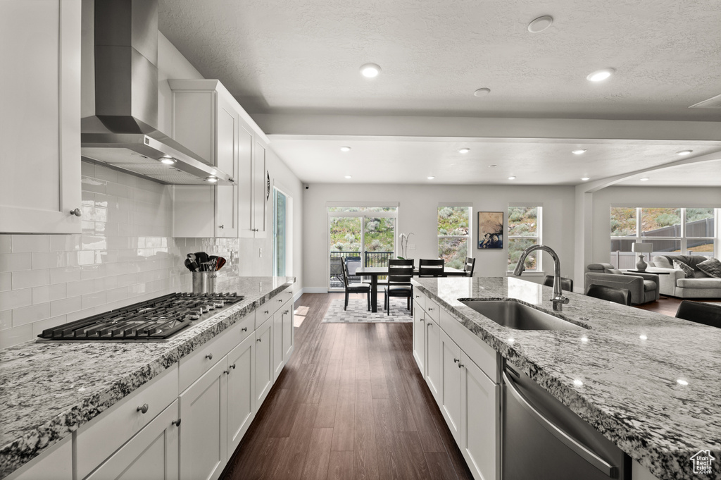 Kitchen with wall chimney range hood, appliances with stainless steel finishes, dark wood-style flooring, healthy amount of natural light, and recessed lighting