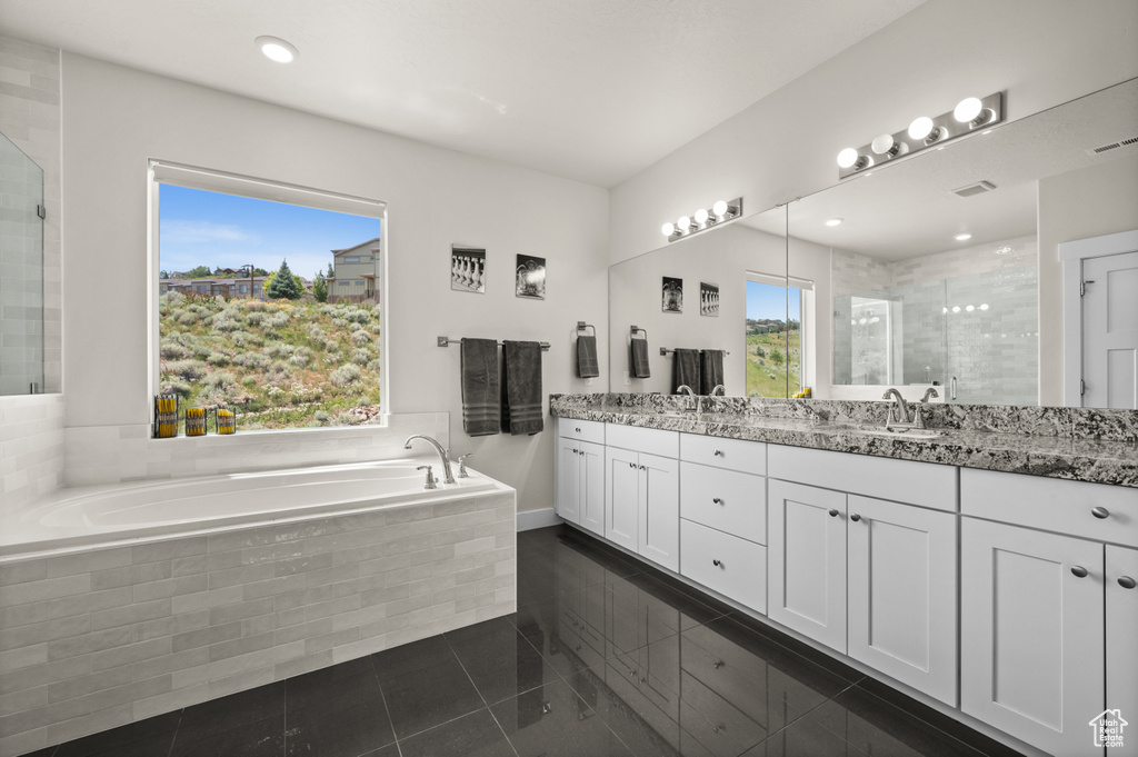 Bathroom with double vanity, a bath, and a tile shower