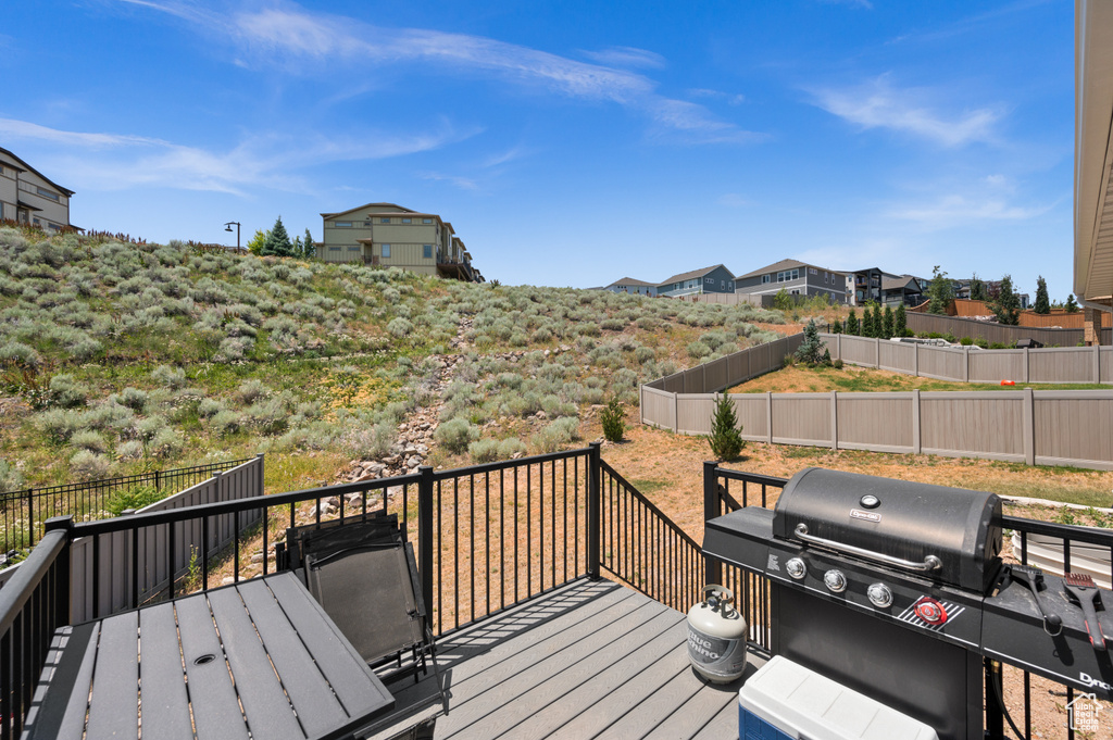 Wooden terrace featuring grilling area, a fenced backyard, and outdoor dining area