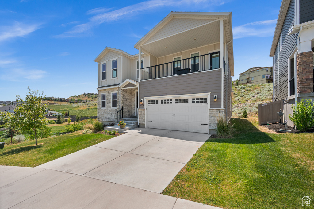View of front of property with a balcony, board and batten siding, stone siding, an attached garage, and concrete driveway