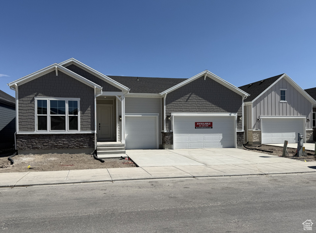 Craftsman-style house featuring a garage, stone siding, concrete driveway, and board and batten siding