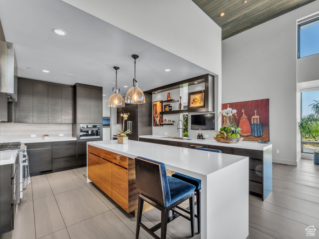 Kitchen with modern cabinets, stainless steel gas stove, a kitchen island, light countertops, and recessed lighting