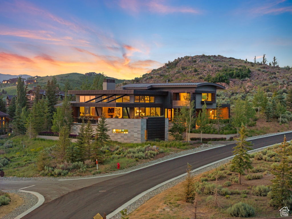 View of front of house with a mountain view, a chimney, and a balcony