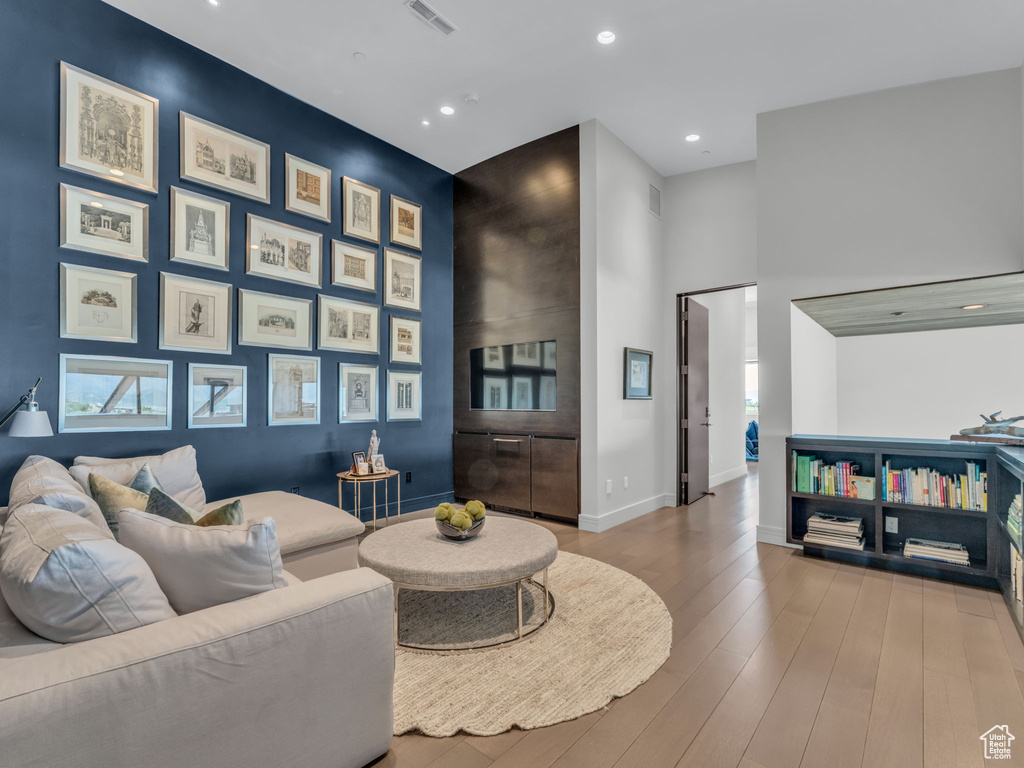 Living area featuring a high ceiling, wood finished floors, and recessed lighting