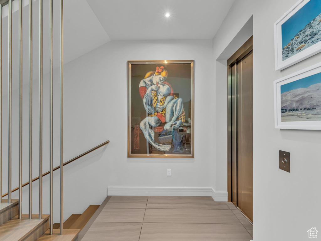 Corridor with lofted ceiling and elevator