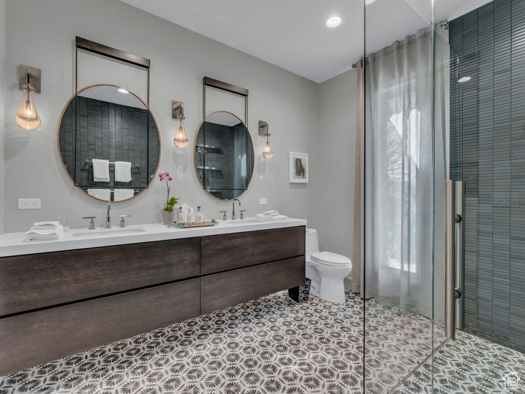 Bathroom featuring double vanity, a shower stall, healthy amount of natural light, and recessed lighting