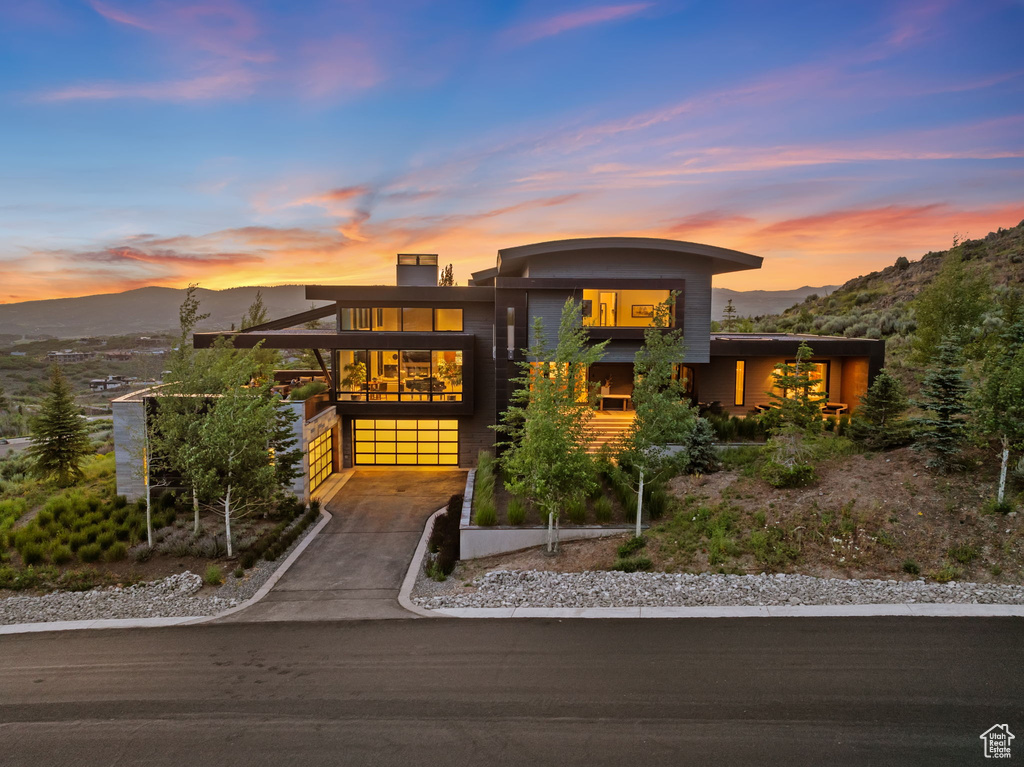Modern home with a mountain view, driveway, an attached garage, and a balcony