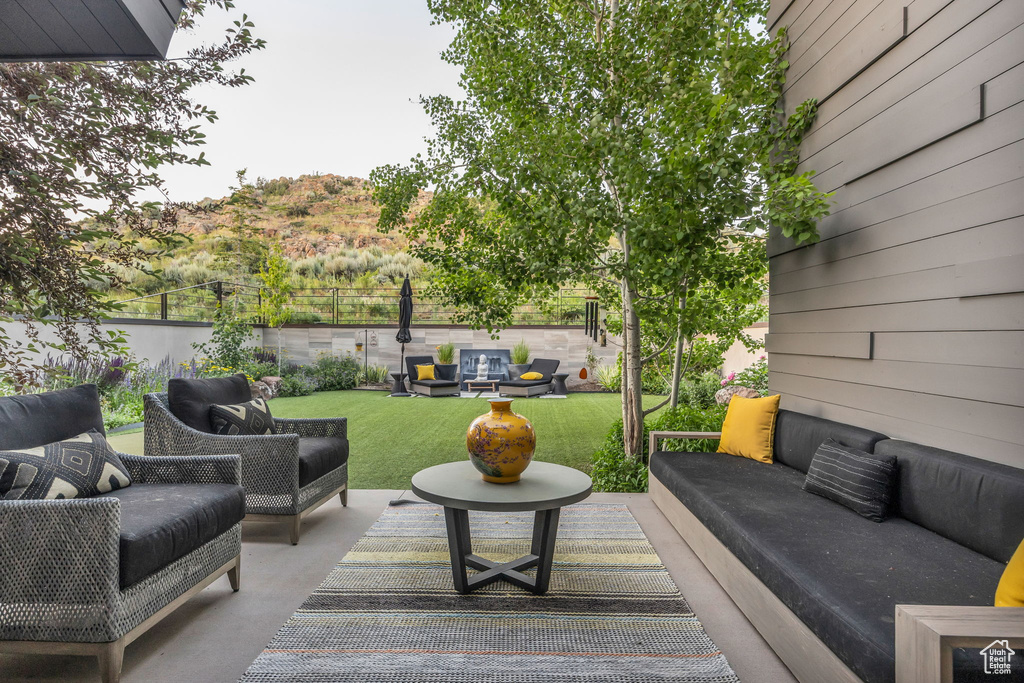 Wooden terrace with outdoor lounge area, a patio, a fenced backyard, and a mountain view