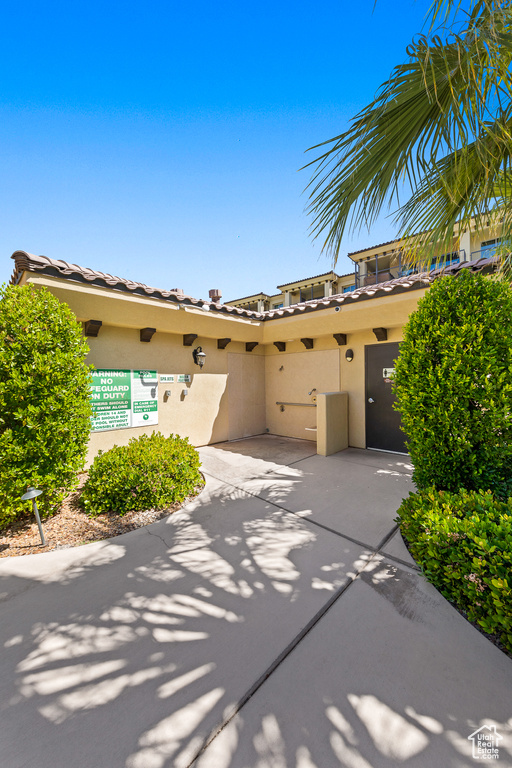 View of front facade with stucco siding, a tile roof, and a patio area
