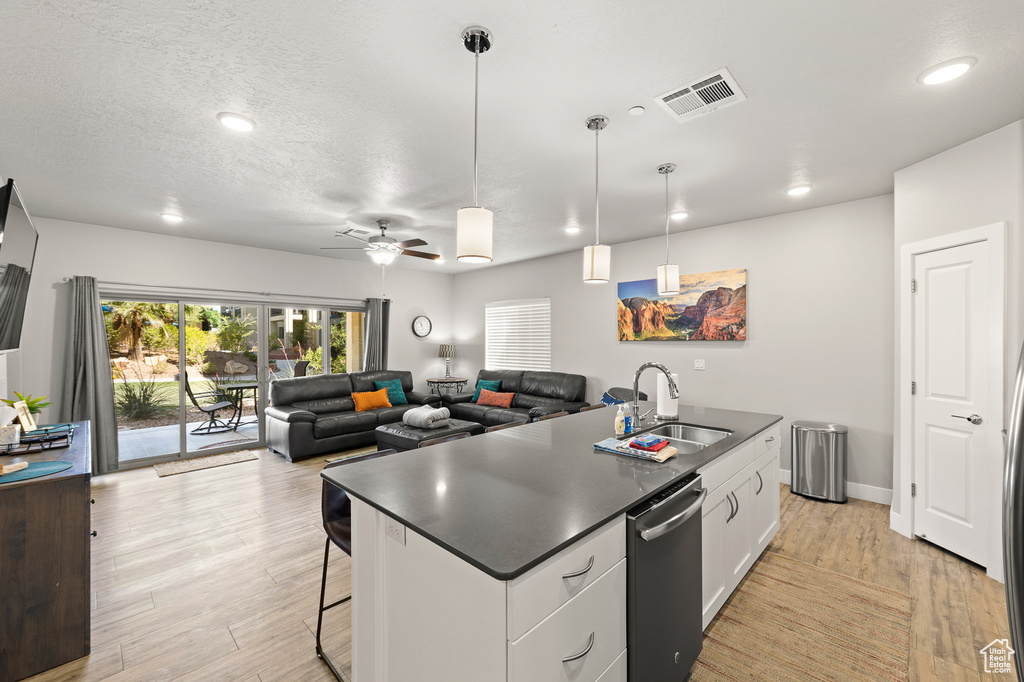 Kitchen with dishwasher, dark countertops, light wood finished floors, recessed lighting, and a textured ceiling