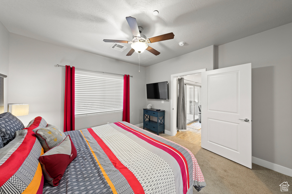 Bedroom featuring light colored carpet, multiple windows, and a ceiling fan