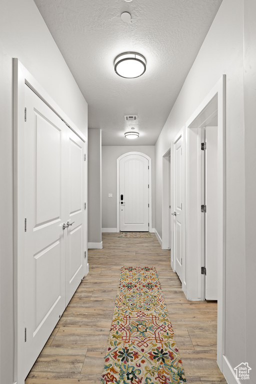 Hallway featuring a textured ceiling and light wood-type flooring