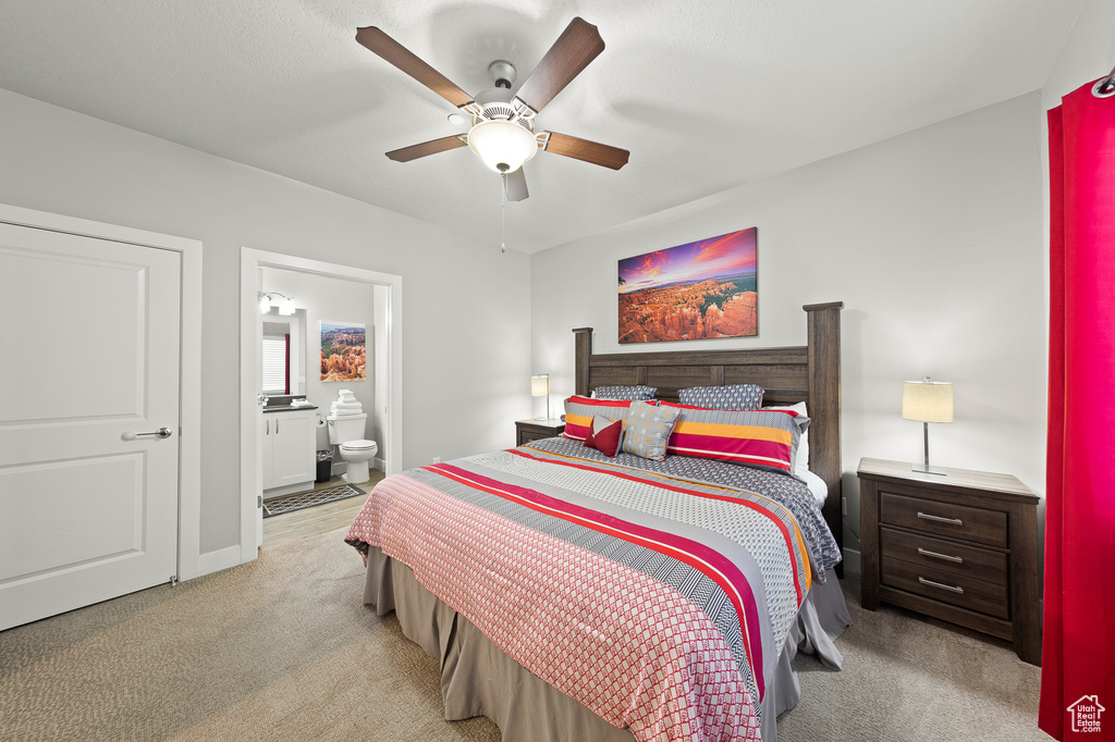Bedroom with light carpet, connected bathroom, and a ceiling fan