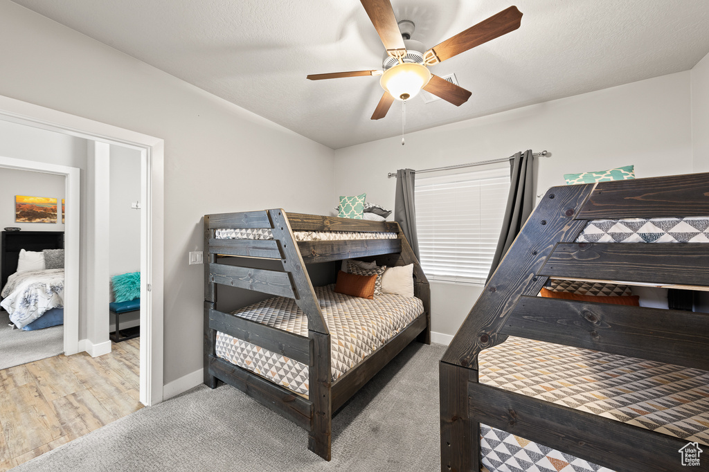 Carpeted bedroom featuring a ceiling fan and wood finished floors
