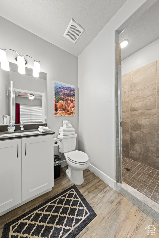 Bathroom featuring vanity, wood finished floors, a stall shower, a textured ceiling, and ceiling fan
