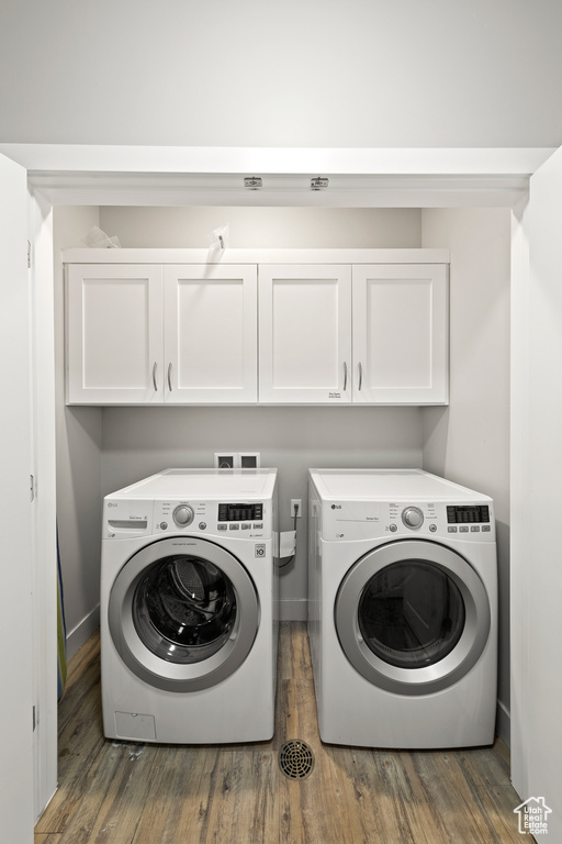 Laundry room with washer and dryer, cabinet space, and wood finished floors