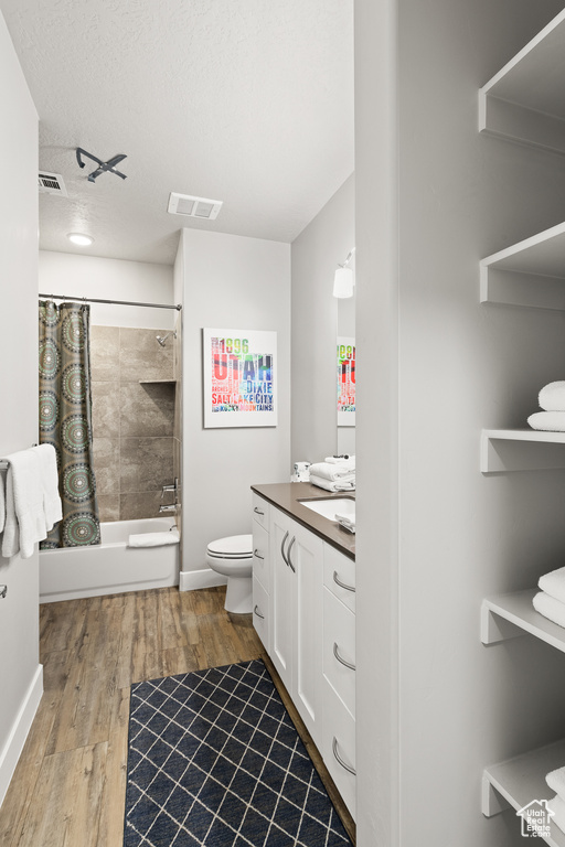 Bathroom with vanity, wood finished floors, shower / tub combo, and a textured ceiling