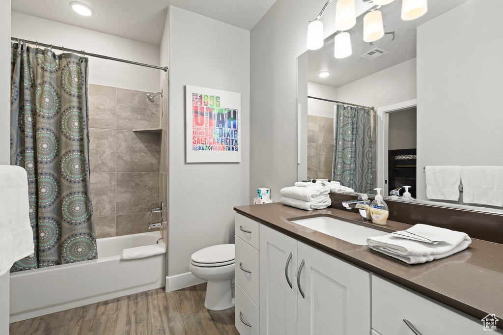 Full bath featuring vanity, shower / tub combo, and wood finished floors