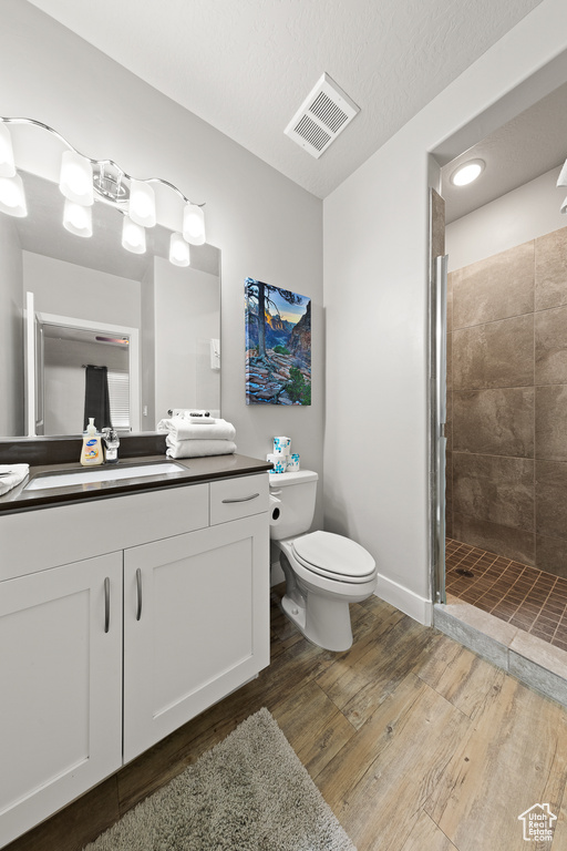 Full bath with wood finished floors, vanity, and a shower stall