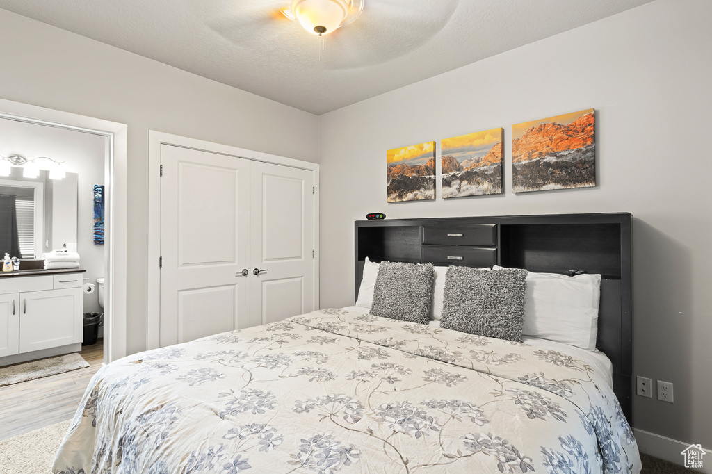 Bedroom with a closet, wood finished floors, ensuite bath, and ceiling fan