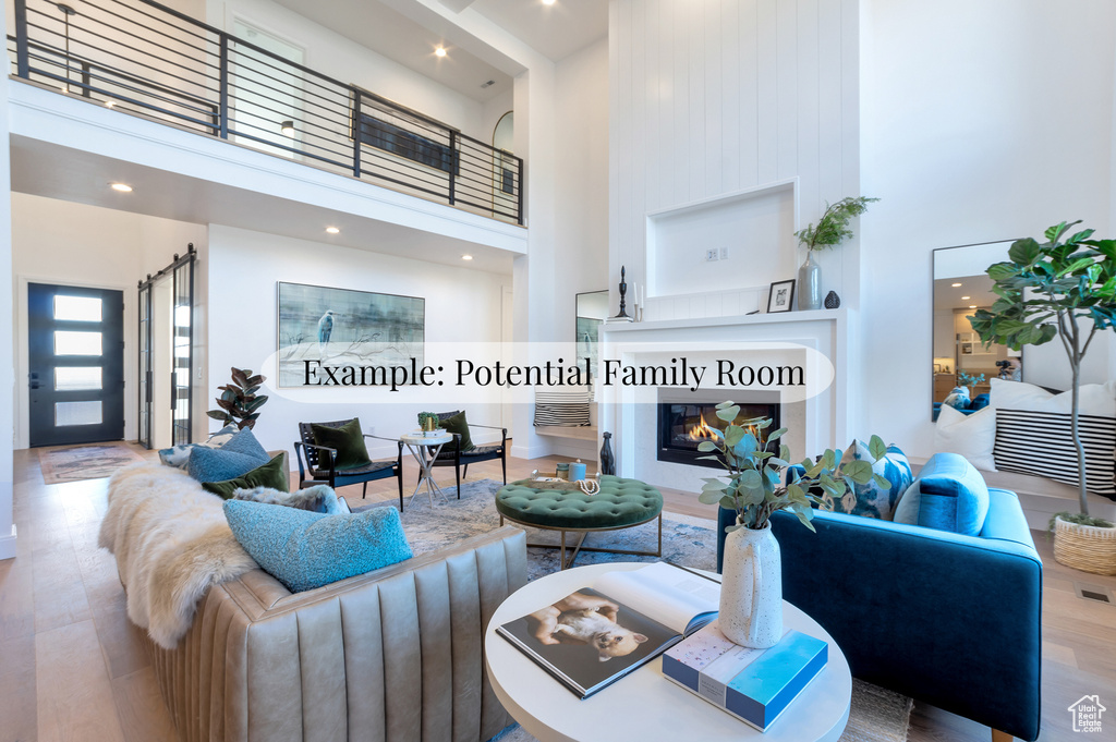 Living area with a towering ceiling, wood finished floors, and a glass covered fireplace