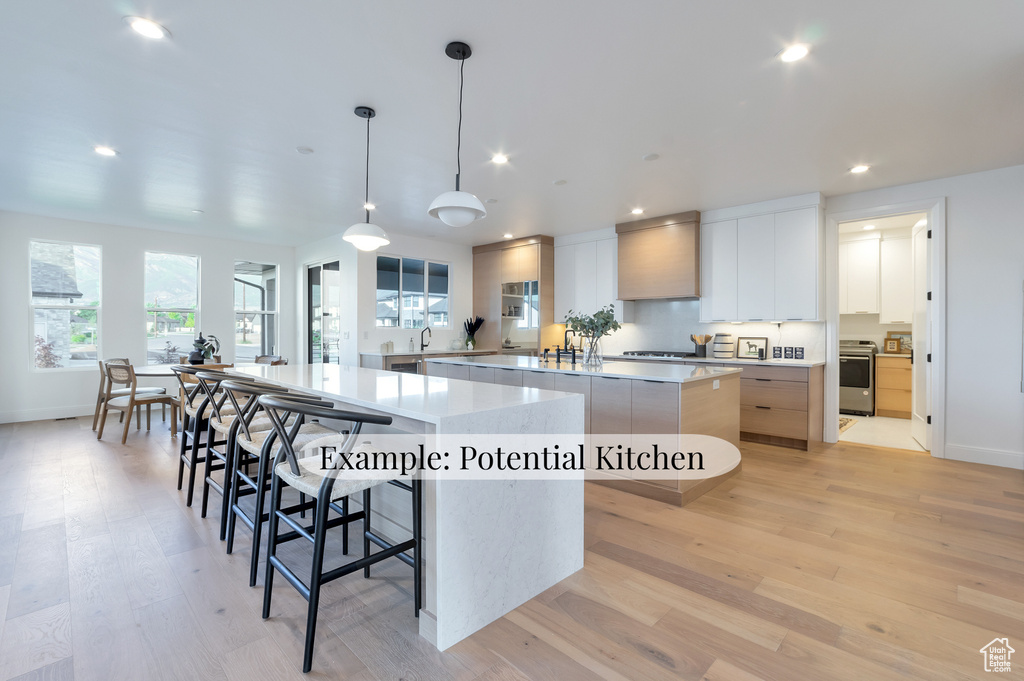 Kitchen with a spacious island, modern cabinets, range, recessed lighting, and light wood-style flooring