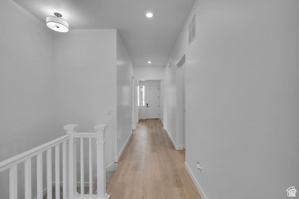 Hall with recessed lighting, light wood-style flooring, and an upstairs landing