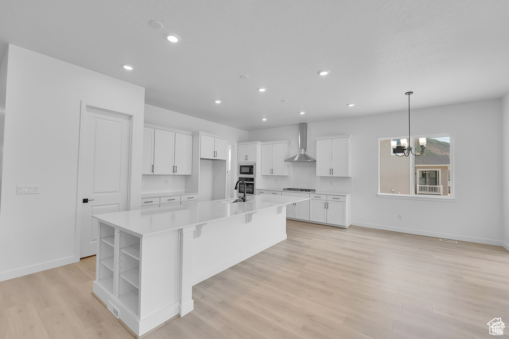 Kitchen with wall chimney exhaust hood, open shelves, white cabinetry, a large island, and built in microwave