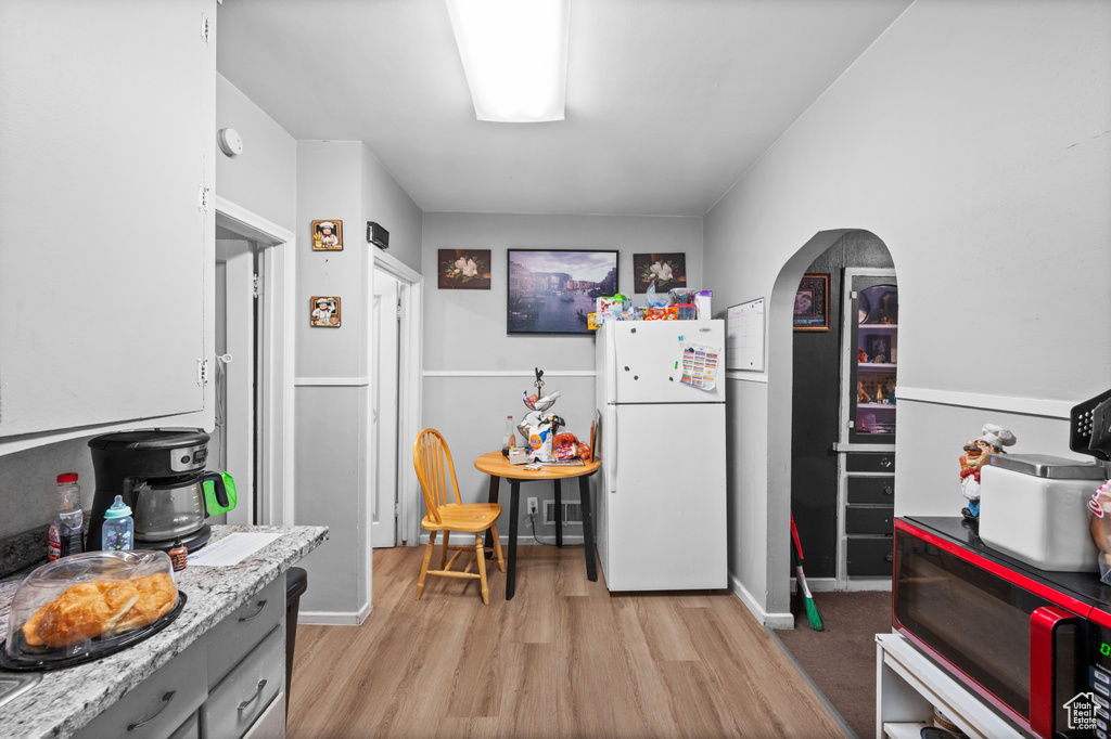 Kitchen with freestanding refrigerator, light wood-type flooring, and arched walkways