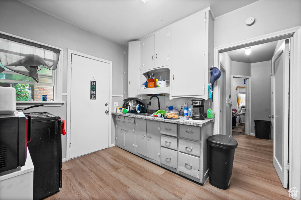 Kitchen featuring light wood-style floors, open shelves, light countertops, and stove