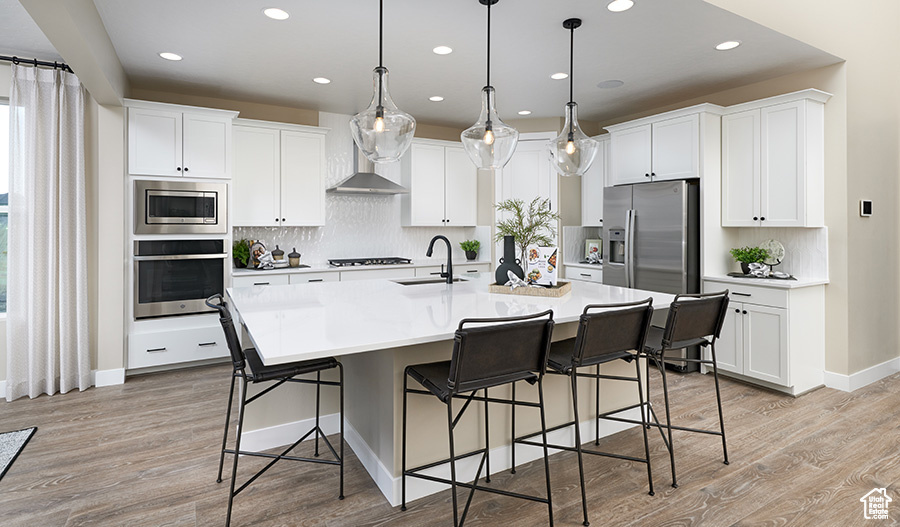 Kitchen with appliances with stainless steel finishes, recessed lighting, light wood-style flooring, a kitchen breakfast bar, and decorative backsplash