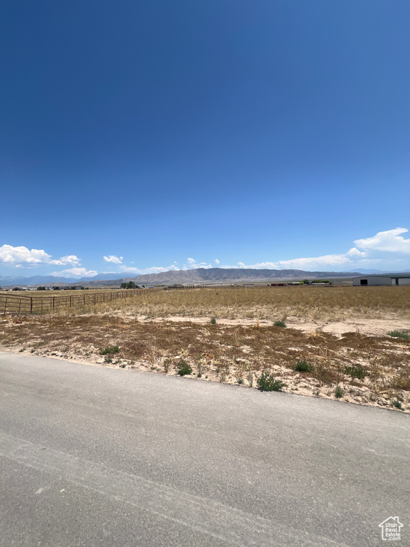 View of asphalt street featuring a view of rural / pastoral area and a mountain view