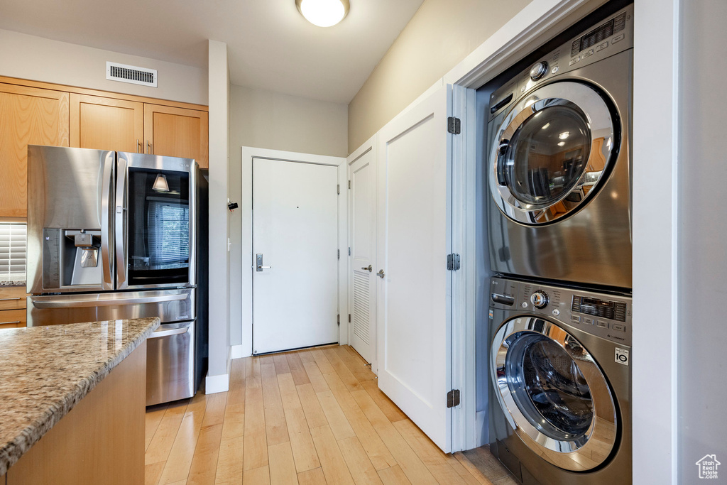 Laundry area featuring stacked washer / dryer and light wood-style floors