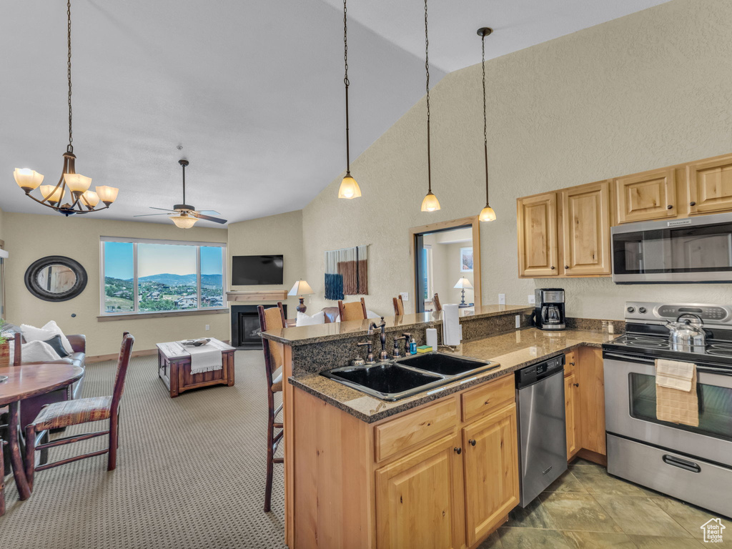 Kitchen with appliances with stainless steel finishes, open floor plan, a ceiling fan, a peninsula, and high vaulted ceiling