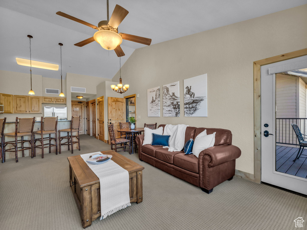 Living area featuring light carpet, a chandelier, a ceiling fan, and high vaulted ceiling