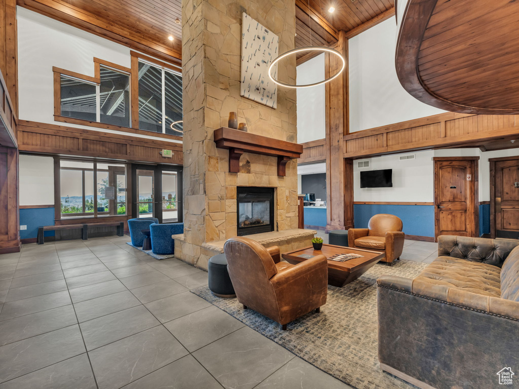 Living room with wooden ceiling, high vaulted ceiling, tile patterned flooring, and a fireplace