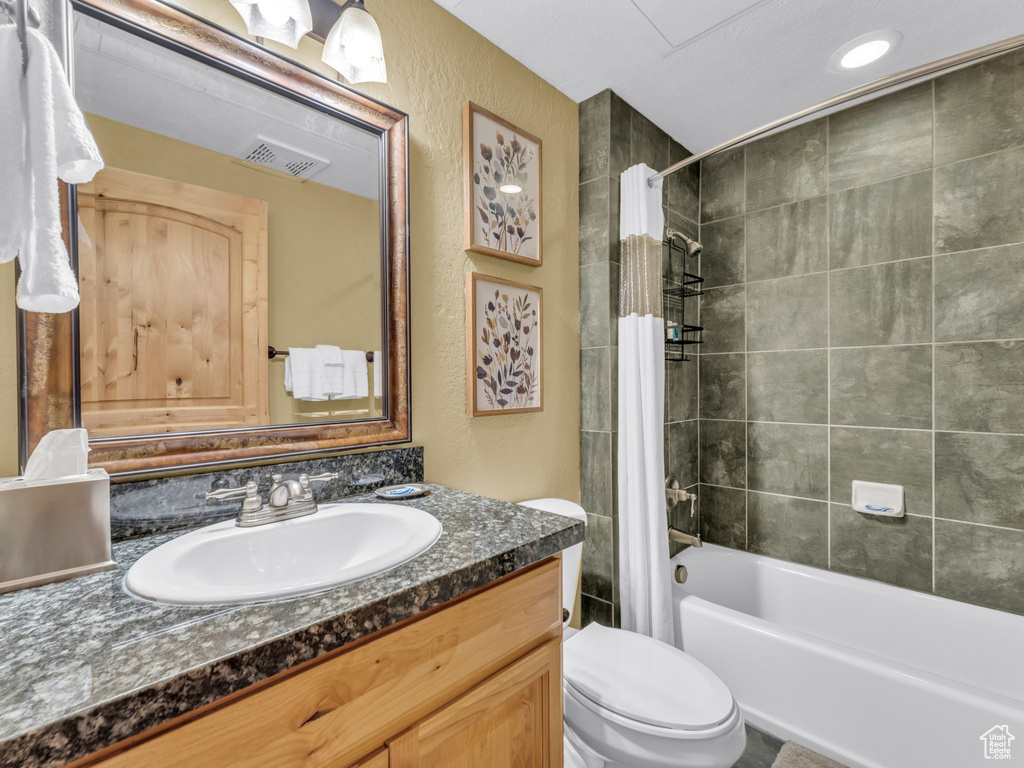 Bathroom with vanity, shower / bath combination with curtain, and a textured wall